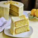 Layered yellow velvet cake with cream cheese frosting, garnished with yellow sprinkles and fresh flowers.